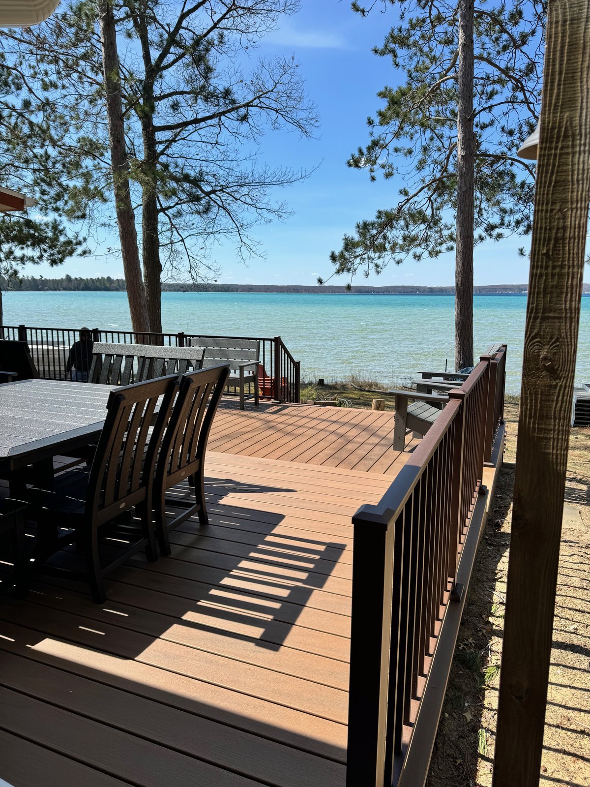 Lakeside composite deck with dining set and umbrella overlooking the water in West Michigan