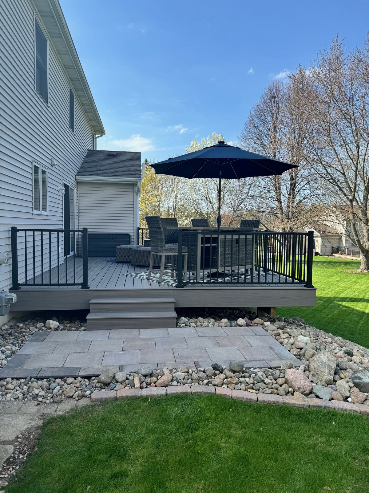Custom backyard deck with umbrella and patio furniture in West Michigan